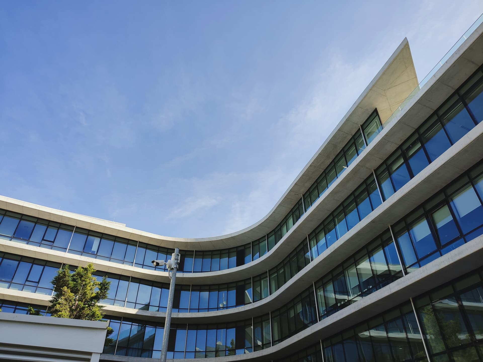 Curved modern office building facade with a street light in front