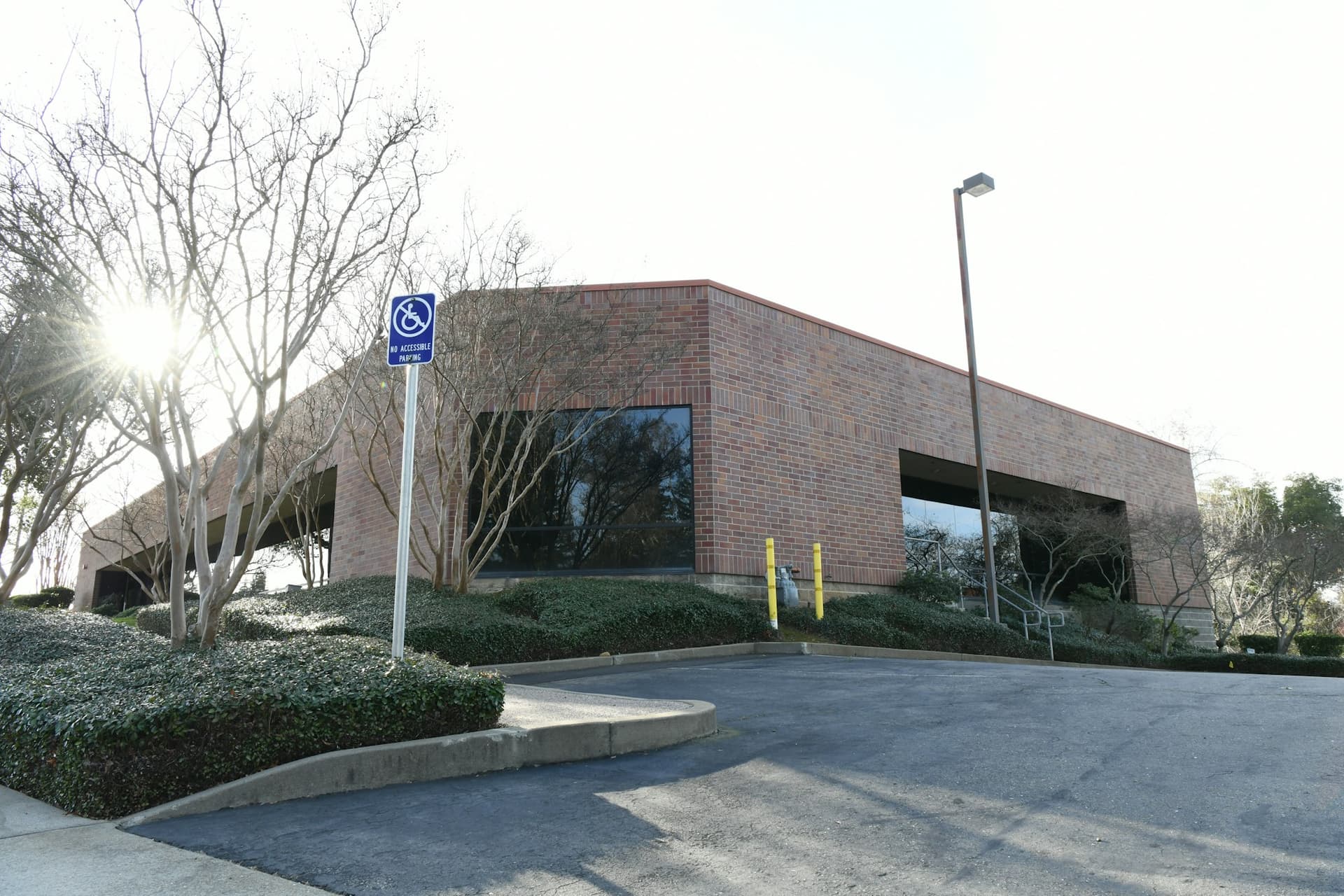 Brick office building with large windows and bare trees in sunlight