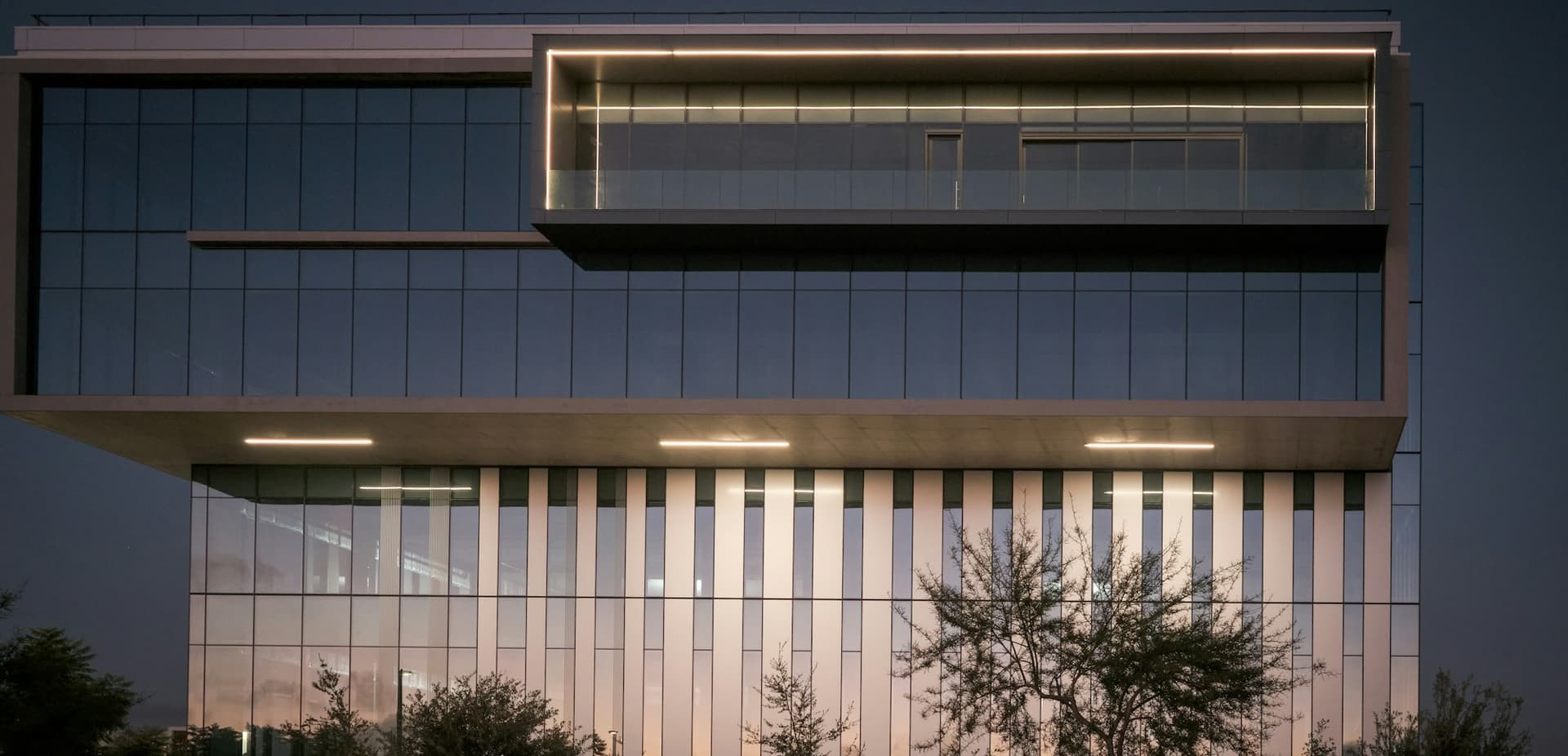Modern office building exterior at dusk with interior lights on